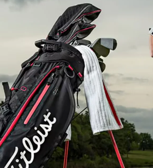 Golf bag with clubs and towel on a course, ready for a game on a cloudy day.