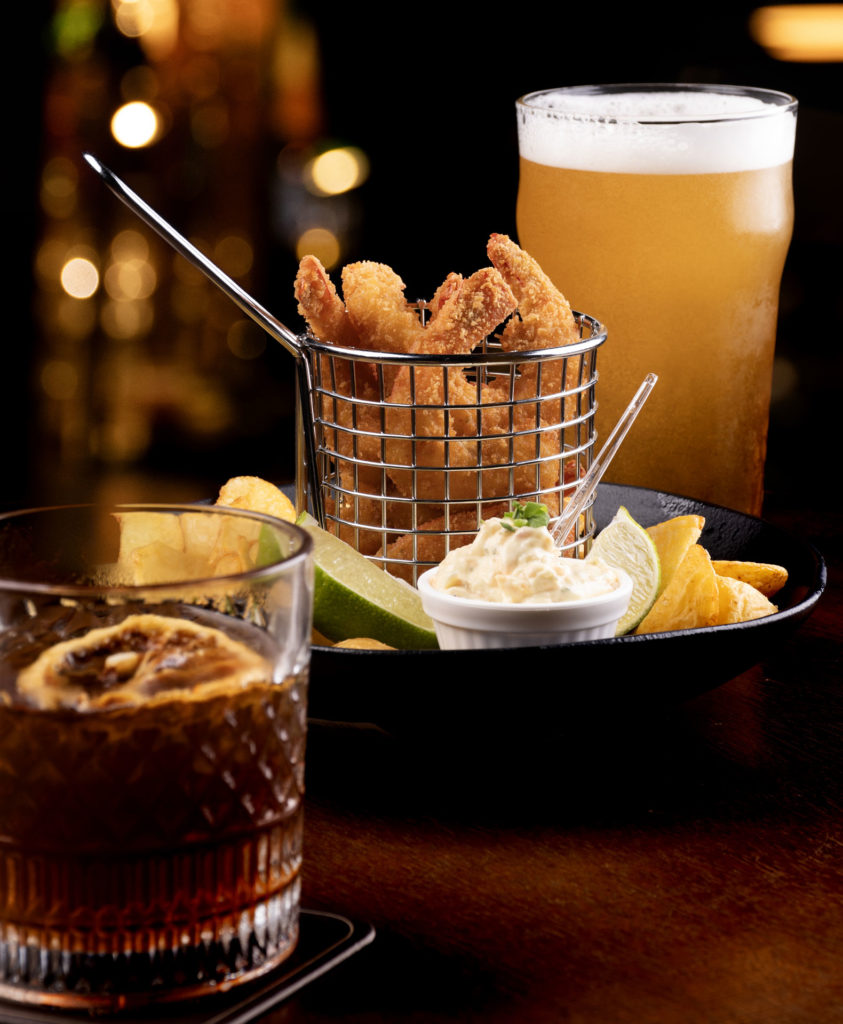 Crunchy shrimp, tangy dip, and refreshing beer on a bar table, ideal for a night out or casual dining.
