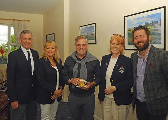 Group of five people smiling in room with framed art and natural light.