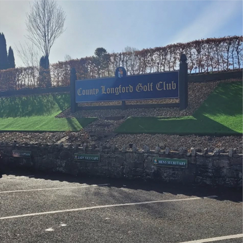 Entrance sign of County Longford Golf Club with green landscaping and sunny sky.