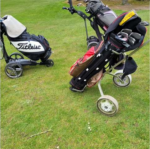 Golf carts with bags and clubs on a lush green course. Sporting equipment outdoors.