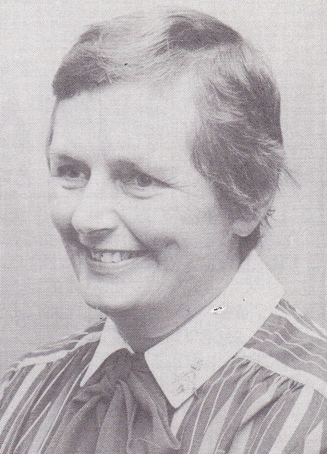 Smiling woman in vintage attire, black and white portrait.