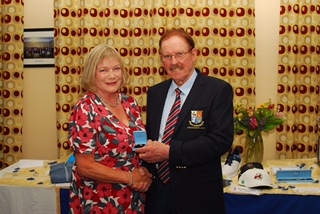 Man and woman shaking hands at an award ceremony in a decorated room.