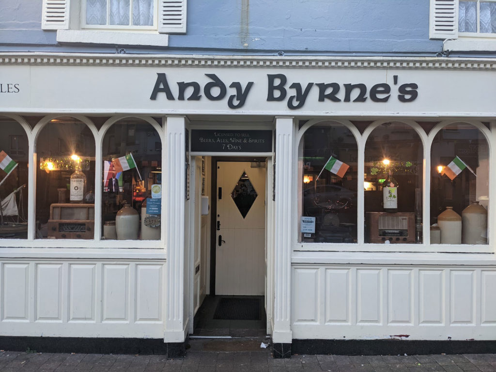Front view of Andy Byrne's pub with Irish flags, cozy interior, and charming traditional facade.