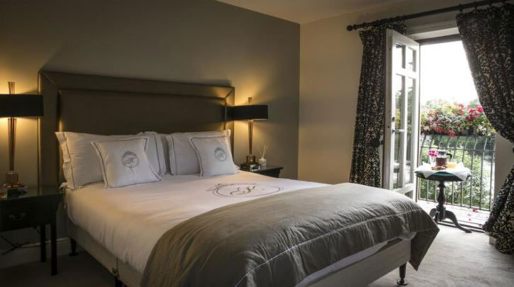 Elegant hotel room with a comfortable bed, stylish decor, and a balcony view with flowers.