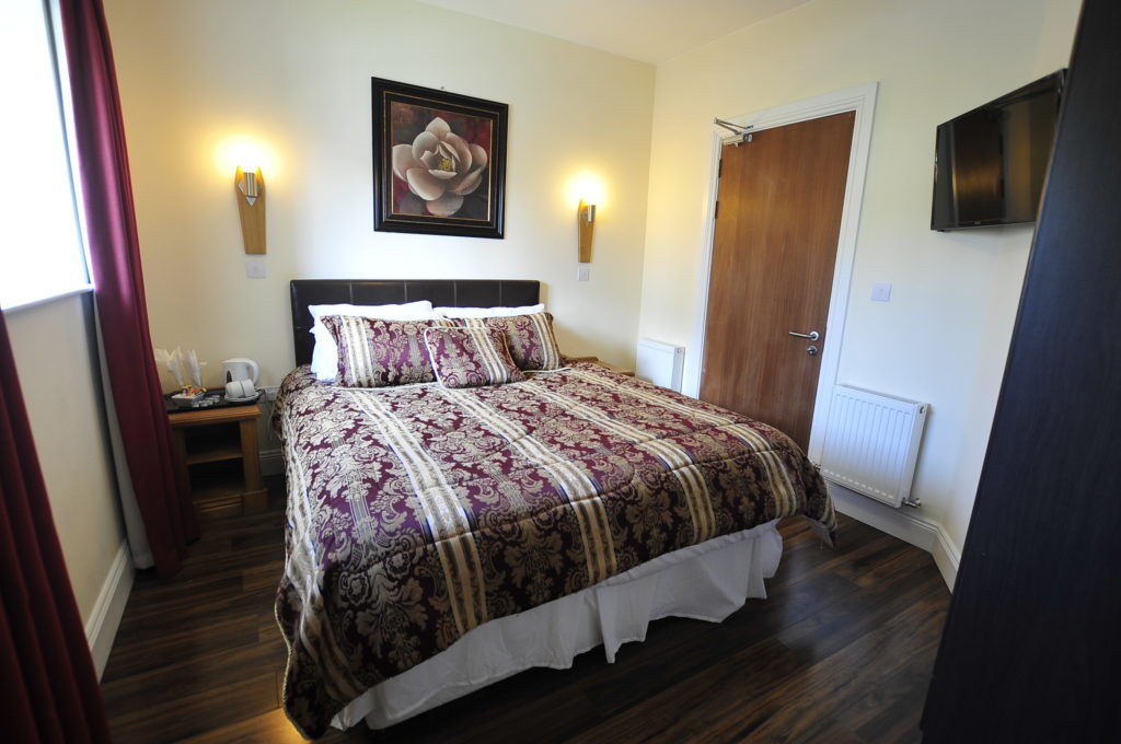 Cozy hotel room with elegant decor, floral artwork, and plush bedding for a comfortable stay.
